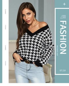 Detail of V-neck houndstooth knit sweater paired with a stylish leather belt and jeans