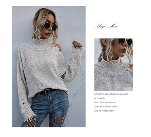 Close-up of off-white knit sweater featuring rainbow specks and frayed shoulder detail