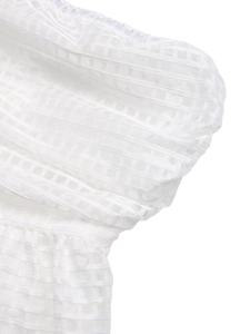 Détail du tissu en résille blanc avec motif jacquard rayé et texture de manche froncée