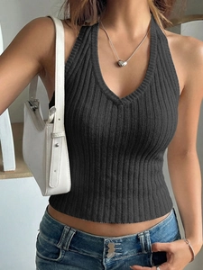Detail of a black ribbed knit halter neck top paired with jeans and a stylish handbag