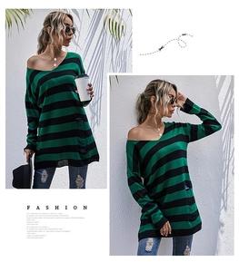 Detail shot of distressed hem with ripped holes on a green and black striped sweater