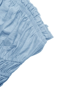 Detailed view of sky blue smocked fabric texture with elegant ruffle edge finish