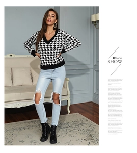 Detail of V-neck houndstooth knit sweater paired with blue ripped jeans and black boots