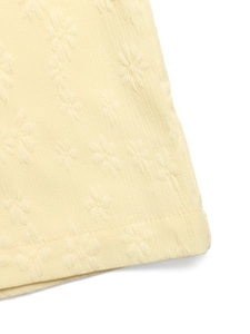 Detail of pale yellow sleeveless jumpsuit showing jacquard floral fabric and stitching