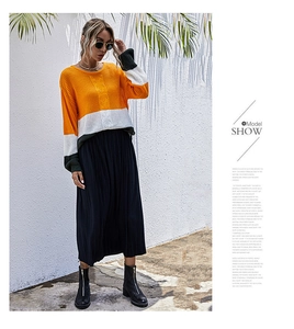 Détail d'un pull en maille color-block avec une jupe plissée et des bottines