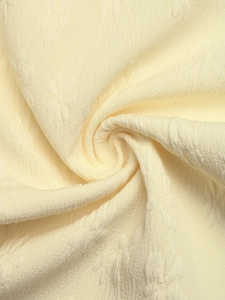 Close-up of elegant beige jacquard fabric texture with intricate embossed floral patterns