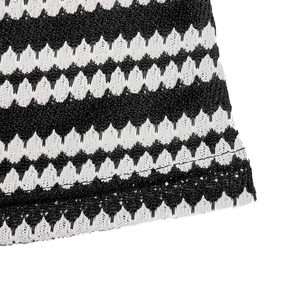 Close-up of black and white striped knit fabric with wavy crochet texture and neat hem