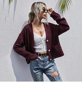 Detail der burgunderroten Strickjacke mit V-Ausschnitt, großen Knöpfen und Taschen