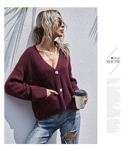 Detail der burgunderroten Strickjacke mit V-Ausschnitt, bunten Punkten und weißen Knöpfen