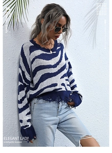 Detail of blue zebra pattern knit sweater featuring frayed hem and distressed tassel finish