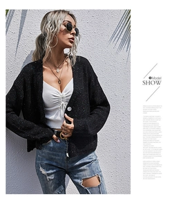 Detail eines schwarzen Strick-Cardigans mit bunten Flecken und Knopfleiste bei einer Frau
