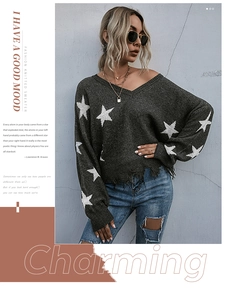 Detail of distressed hem and white star pattern on dark grey V-neck knitted sweater