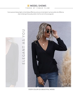 Detail view of a black long-sleeved ribbed wrap top with a deep V-neck and waist tie design