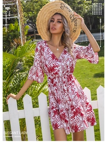 Detail of red leaf print on white V-neck dress with elegant ruffled sleeves and hem