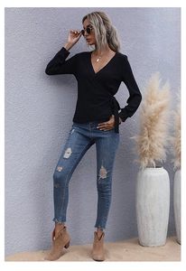Detail of a black V-neck wrap top with ribbed knit texture and side-tie waist design