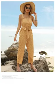 Detail of summer yellow floral jumpsuit with ruffle neckline and waist tie on the beach