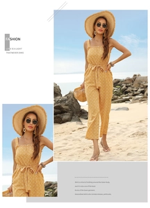 Detail of yellow floral jumpsuit featuring ruffled neckline and waist tie on the beach