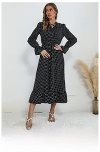 Détail de la robe noire à pois à col en V avec cordon de serrage et ourlet à volants