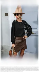 Detail of loose black sweatshirt featuring delicate white pearl embellishments on shoulder