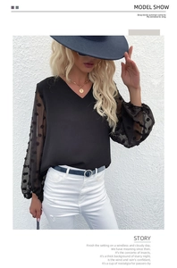 Detail view of black V-neck chiffon blouse with polka dot mesh sleeves on a female model
