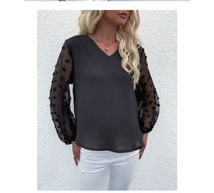 Detail of sheer mesh sleeves with textured polka dots on a black V-neck lace chiffon blouse