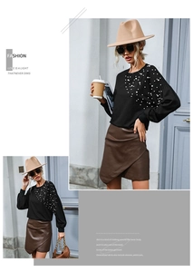 Detail of black crewneck sweatshirt with radiant white pearl beads and brown leather skirt