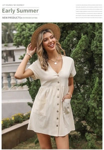 Detail of beige V-neck button-down dress featuring front pockets and cotton linen texture
