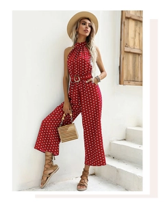 Detail of red polka dot halter neck jumpsuit with a round buckle belt in a resort style