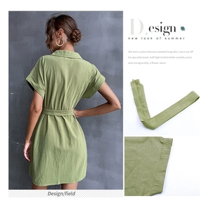 Detail view of green cotton linen shirt dress showing waist tie and rolled sleeve cuffs