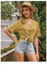 Dettaglio camicia gialla in cotone e lino con maniche corte, scollo a V e nodo sull'orlo