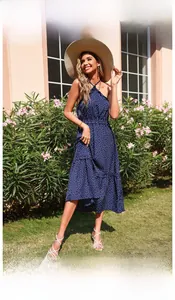 Close-up of a navy polka dot halter dress with layered ruffle hem and backless design