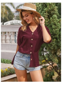 Dettaglio di camicia estiva bordeaux con scollo a V, tessuto operato e bottoni in legno