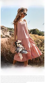 Detailed tiered hemline of a pink linen cotton backless sundress in a summer field