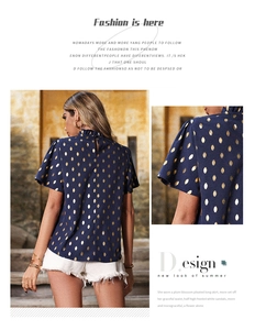 Dettaglio della camicetta blu navy a maniche corte con motivi dorati e collo a pieghe