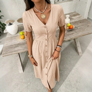 Detailed close-up of apricot cotton linen dress with V-neck and decorative bow cuffs