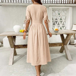 Back view of a beige cotton linen V-neck dress featuring tied cuffs and a cinched waistline