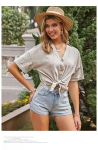 Dettaglio camicia in lino marrone chiaro con scollo a V e nodo sull'orlo per l'estate