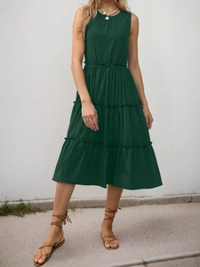 Dettaglio di un abito lungo senza maniche verde scuro con scollo rotondo e balze