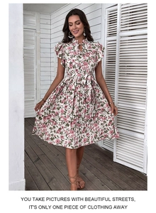 Détail d'une robe plissée fleurie montrant des manches à volants et une taille nouée