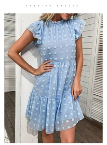 Detail of light blue sleeveless chiffon dress with ruffled collar and 3D textured pom-poms
