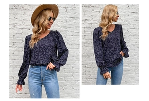Detail of ruffled cuffs and white polka dot print on navy blue long sleeve top