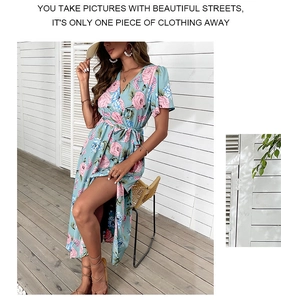 Detail of light blue floral wrap dress with pink roses and high slit on a sunny terrace