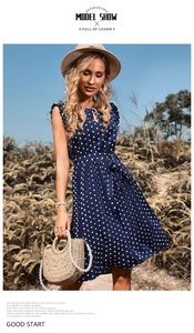 Detailed view of navy blue polka dot dress featuring sleeveless cut and belted waist