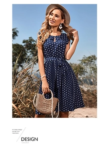 Close-up of pleated dark blue polka dot dress with waist tie and round neckline