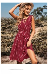 Detail of burgundy polka dot sleeveless pleated dress with waist belt in outdoor sunlight