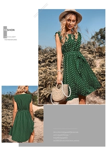Detailed view of dark green polka dot sleeveless dress with waist tie in summer meadow