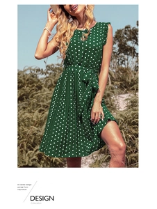 Detail of green polka dot dress featuring hollow neck design and pleated skirt texture