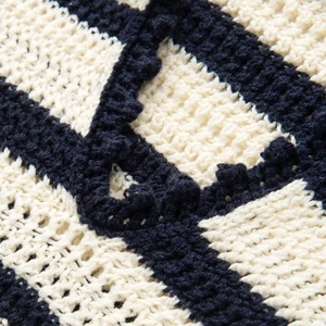 Makrodetail aus dunkelblauem und cremefarbenem Strickstoff mit eingewebtem Buchstaben B