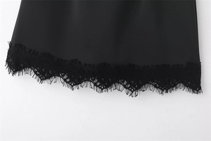 Détail de l'ourlet de la jupe noire avec une bordure délicate en dentelle florale