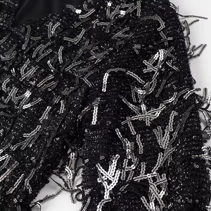 Close-up of black tweed fabric with intricate silver sequins and fringe details